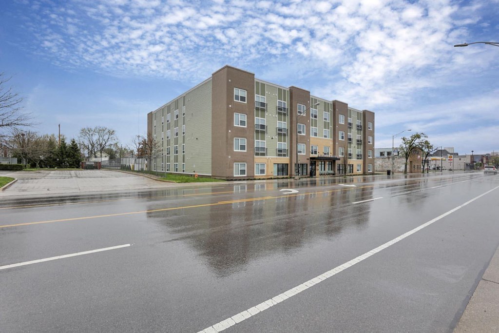 an empty street in front of an apartment building on a rainy day
