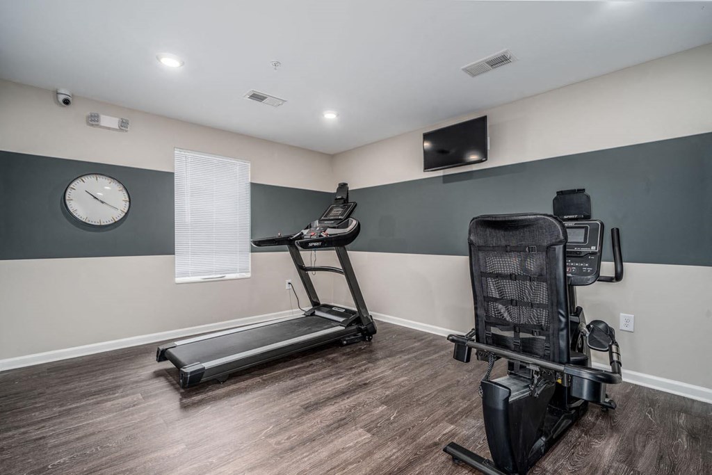 a gym with a treadmill and a clock on the wall