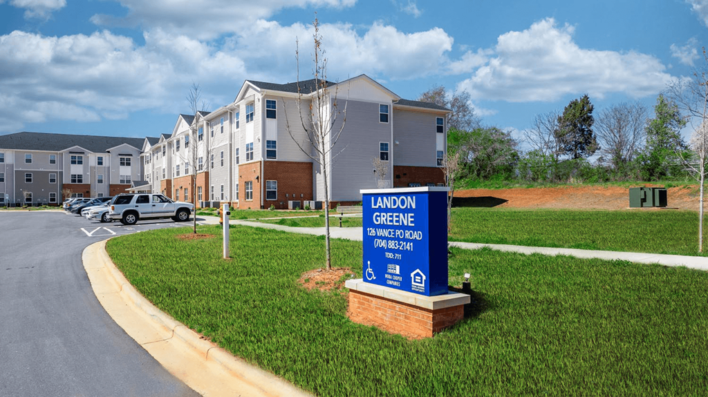 a sign is in the grass in front of an apartment building