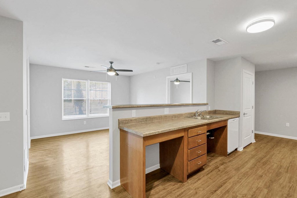 an empty living room with a kitchen with a counter top