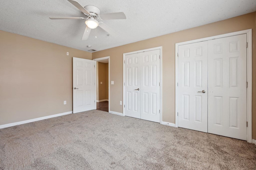 an empty room with white doors and a ceiling fan