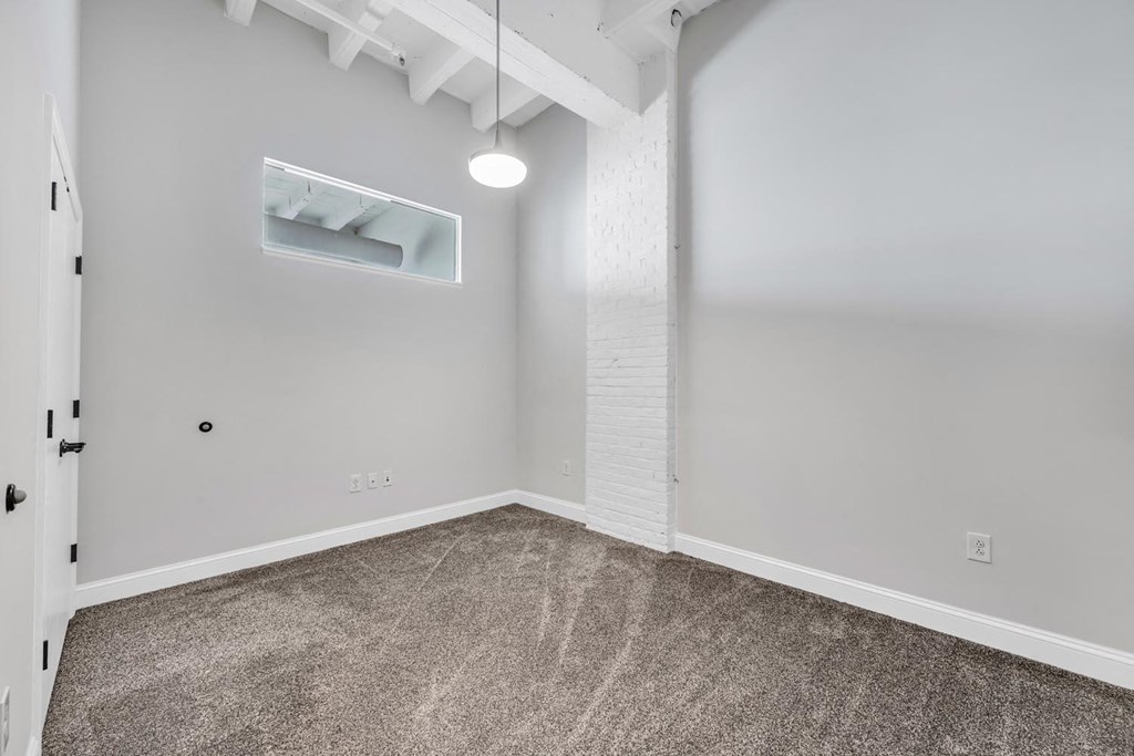 a bedroom with gray carpeting and a white exposed beam on the ceiling