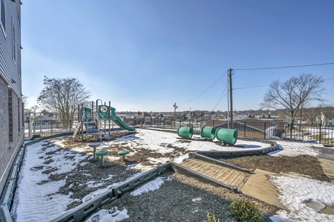 A playground with a green slide and a wooden ramp.