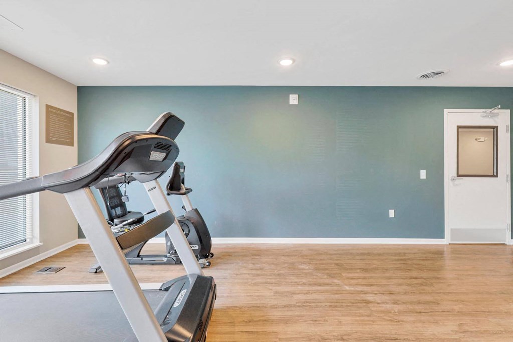 the gym is equipped with a treadmill and a blue wall