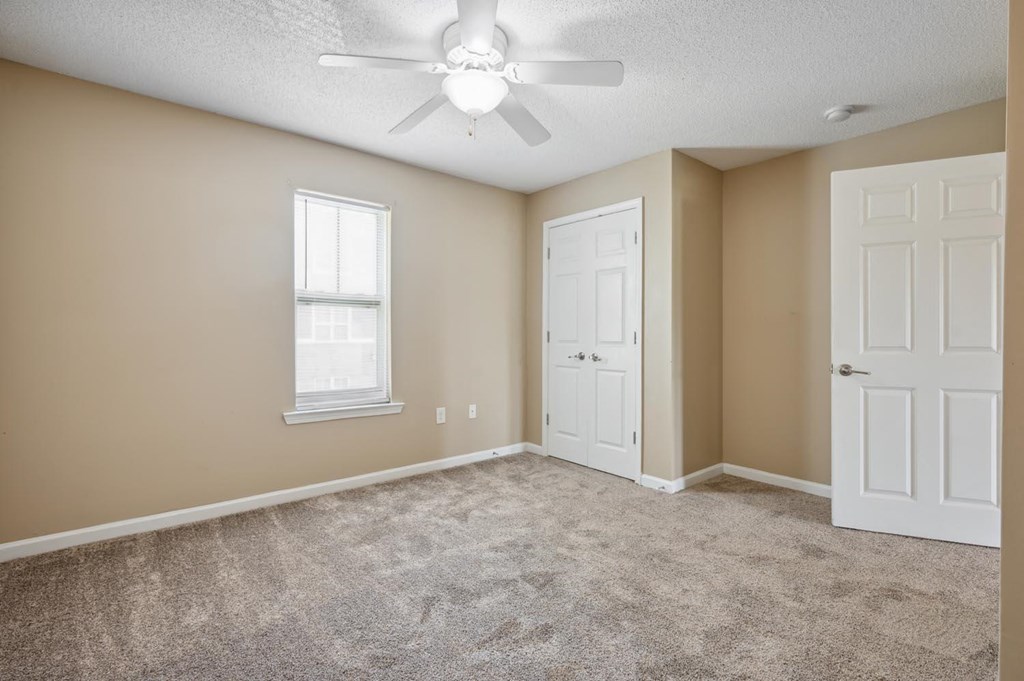 an empty room with a ceiling fan and two doors