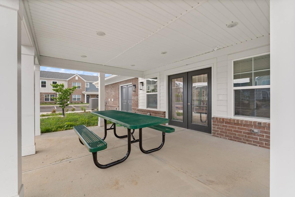 A green table and bench are on a patio.