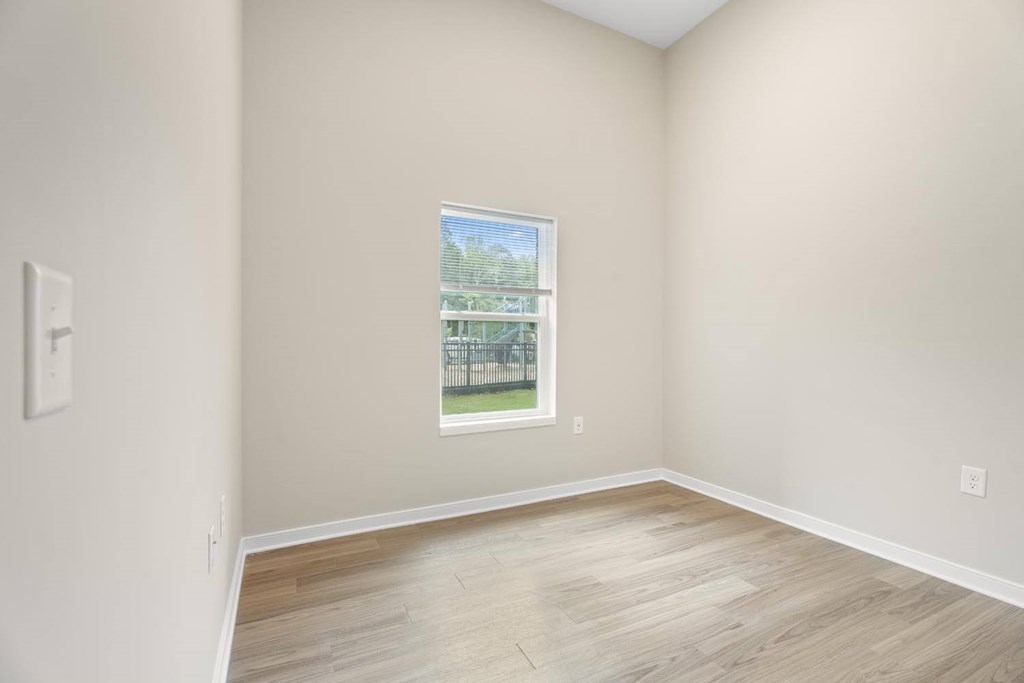 A room with a window and wooden flooring.