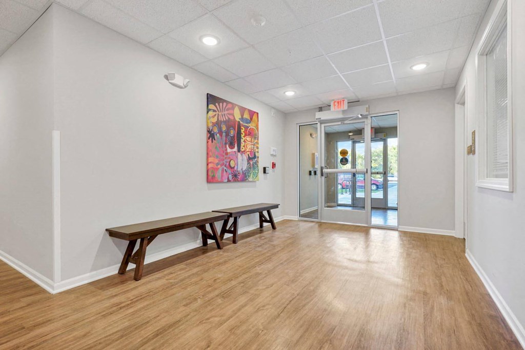 a room with two benches and a door to a hallway with a painting on the