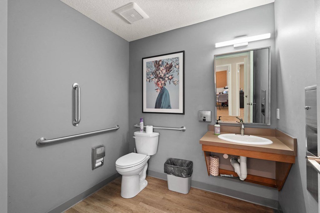 A bathroom with a toilet, sink, and mirror.