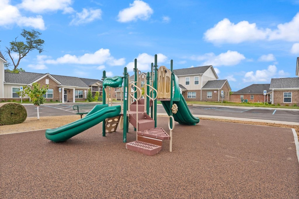A playground with a green slide and a red brick structure.
