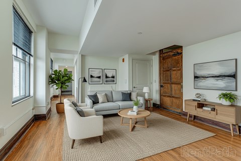 A living room with a grey couch, a coffee table, and a large painting on the wall.