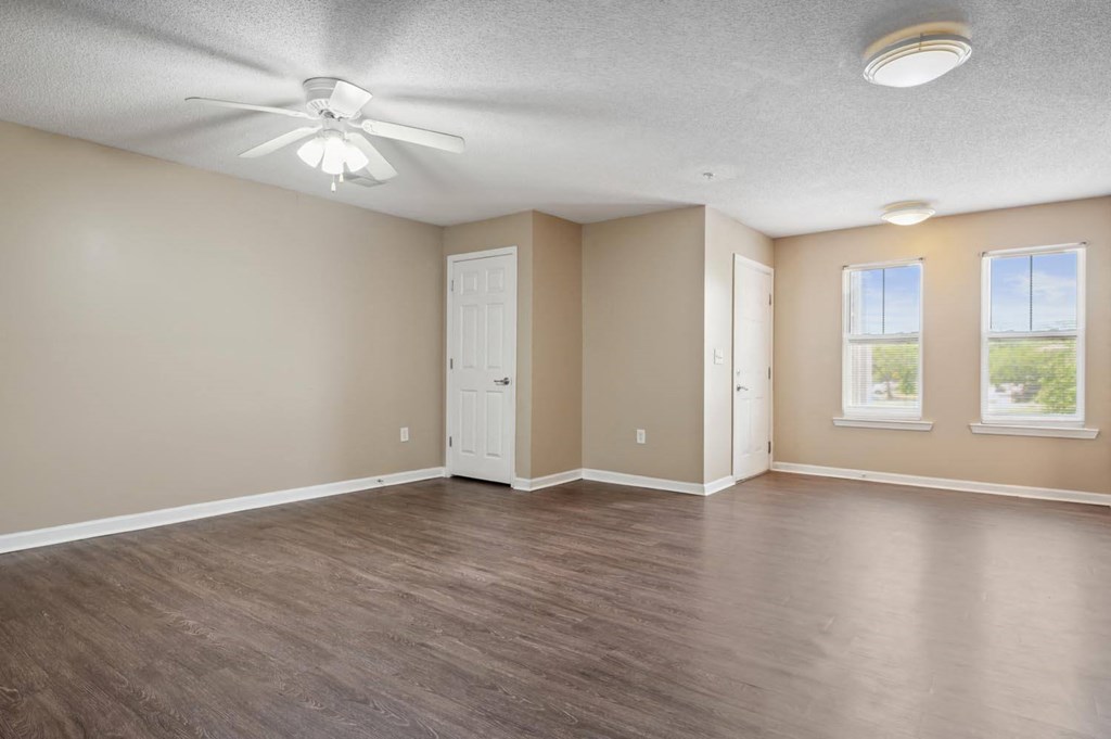an empty living room with wood floors and a ceiling fan