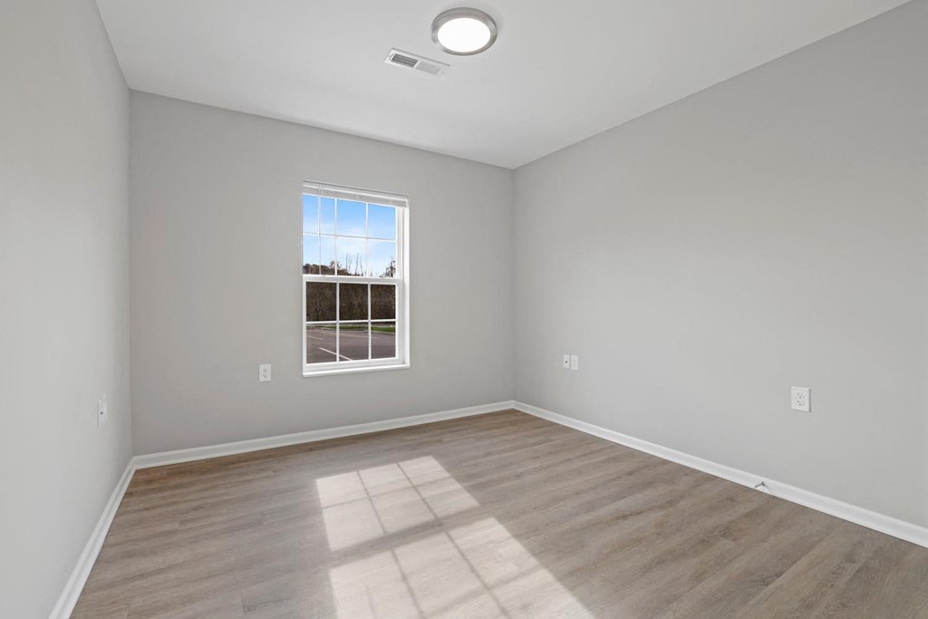 an empty room with wood floors and a window