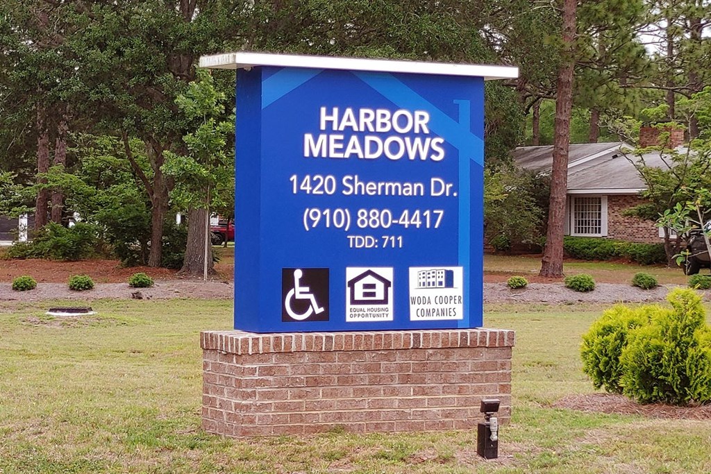 a sign in front of a house that says harbor meadows 144 sherman dr