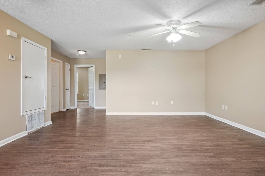 an empty living room with wood floors and a ceiling fan