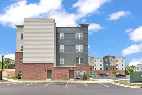 A modern apartment building with a parking lot in front.