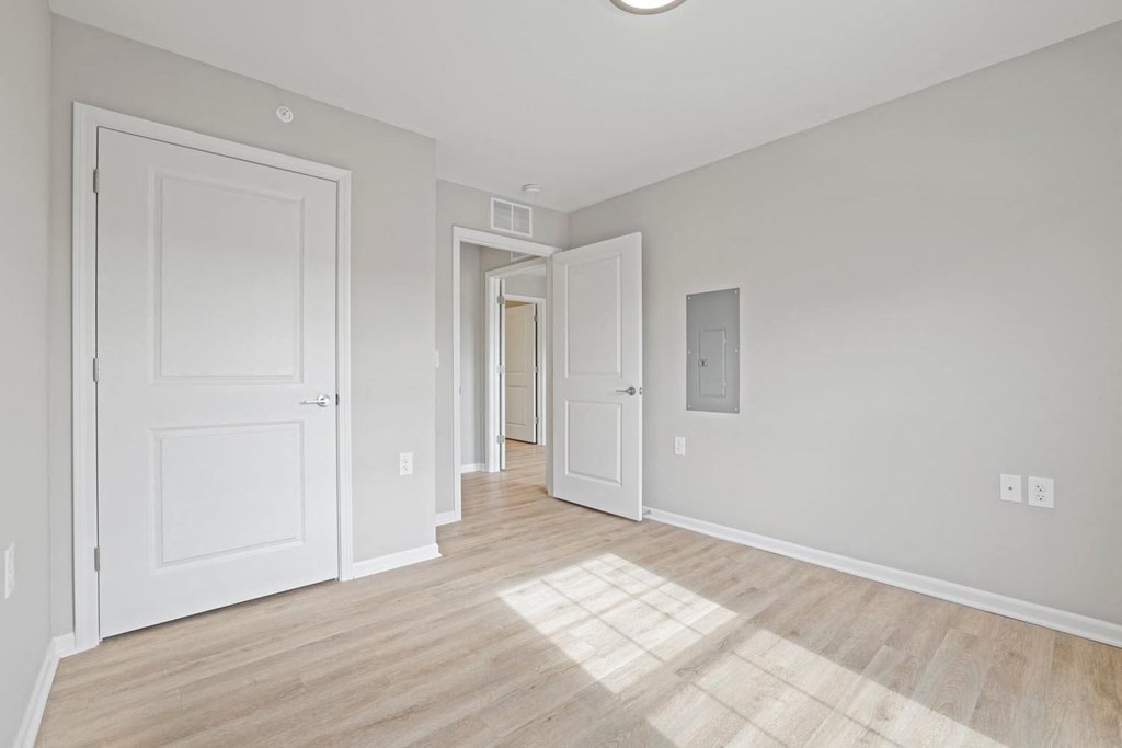 an empty living room with white doors and wood flooring
