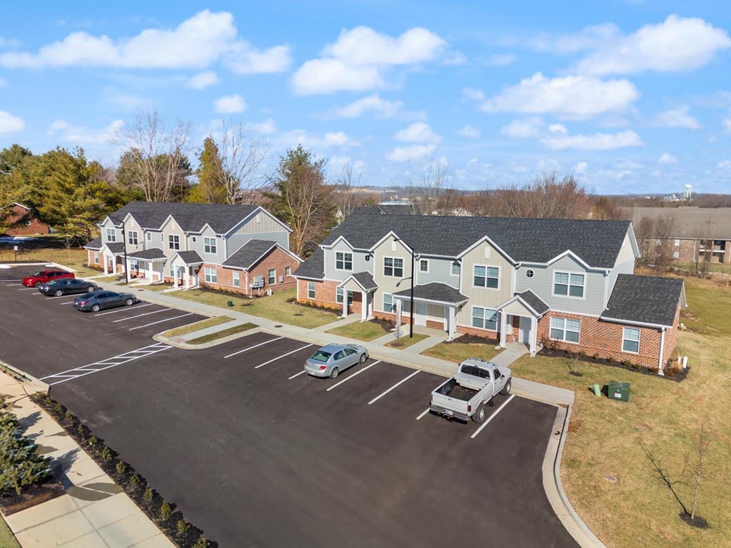 A parking lot in front of a building with cars parked.