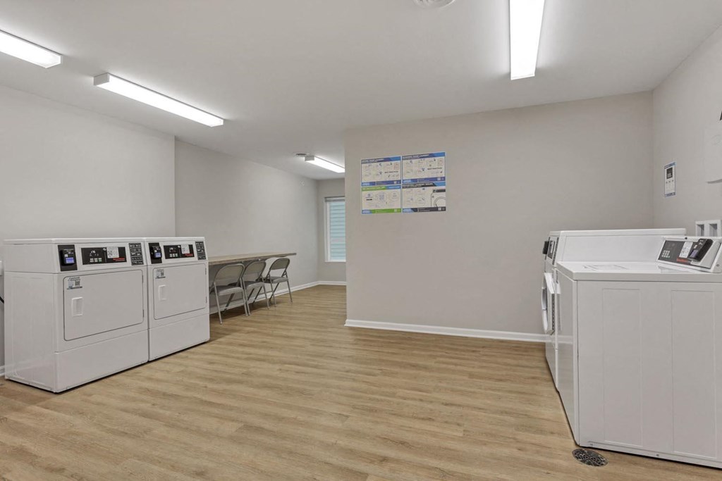 a room with laundry machines and a table with chairs