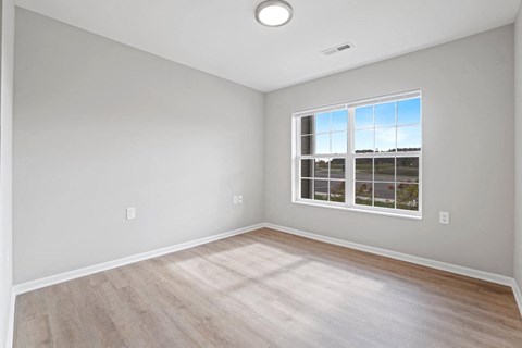 an empty room with wood floors and a window