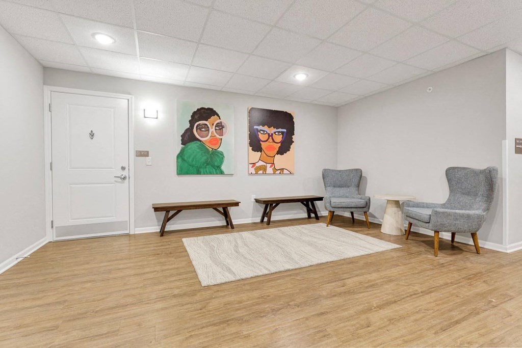 room with chairs and paintings on the wall and a rug