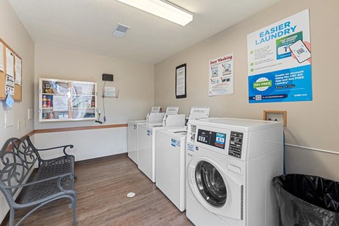 a laundry room with four washing machines and a bench