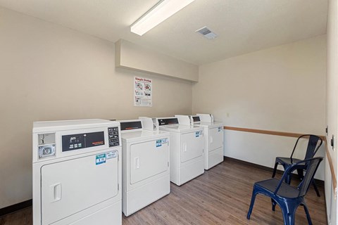 a row of washers and dryers in a room with a chair