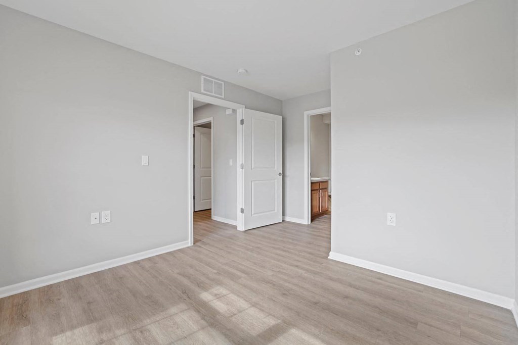 a spacious living room with white walls and wood floors
