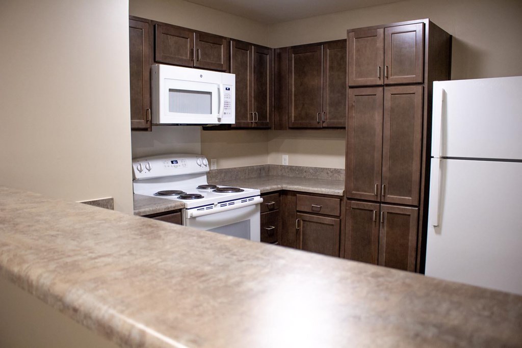 A kitchen with brown cabinets and a white refrigerator.