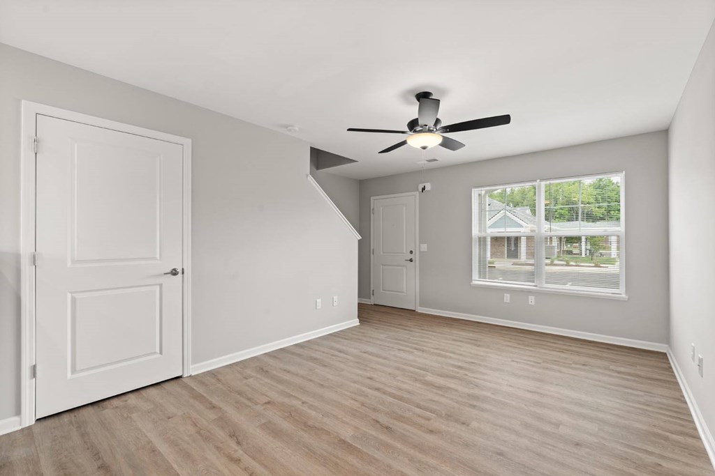 A room with a ceiling fan and a window with a view of a house.