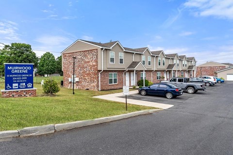 an apartment complex with cars parked in a parking lot