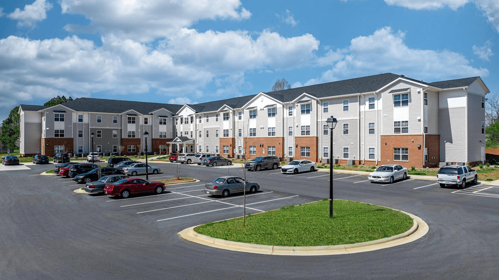 a parking lot with cars in front of an apartment building