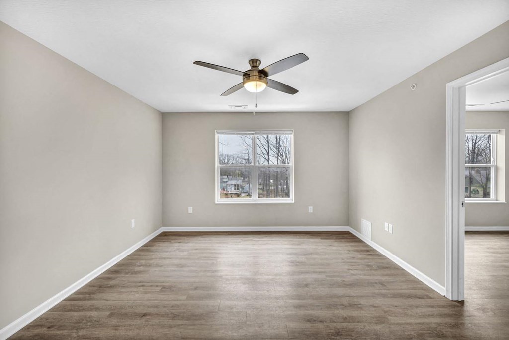 an empty living room with a ceiling fan and a window