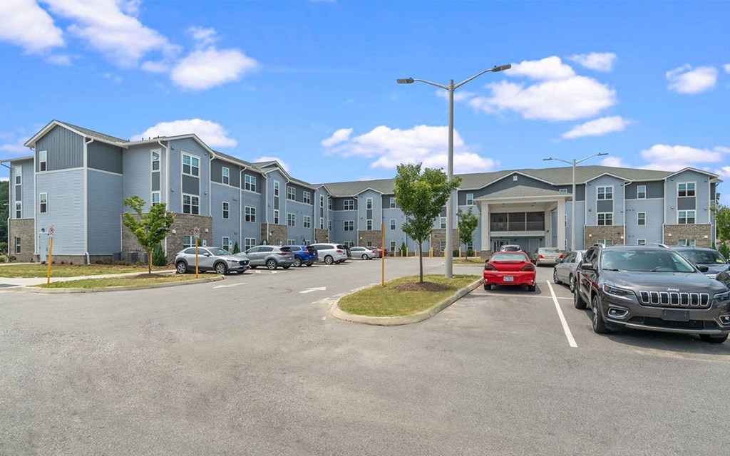 an apartment complex with a parking lot and cars in front of it