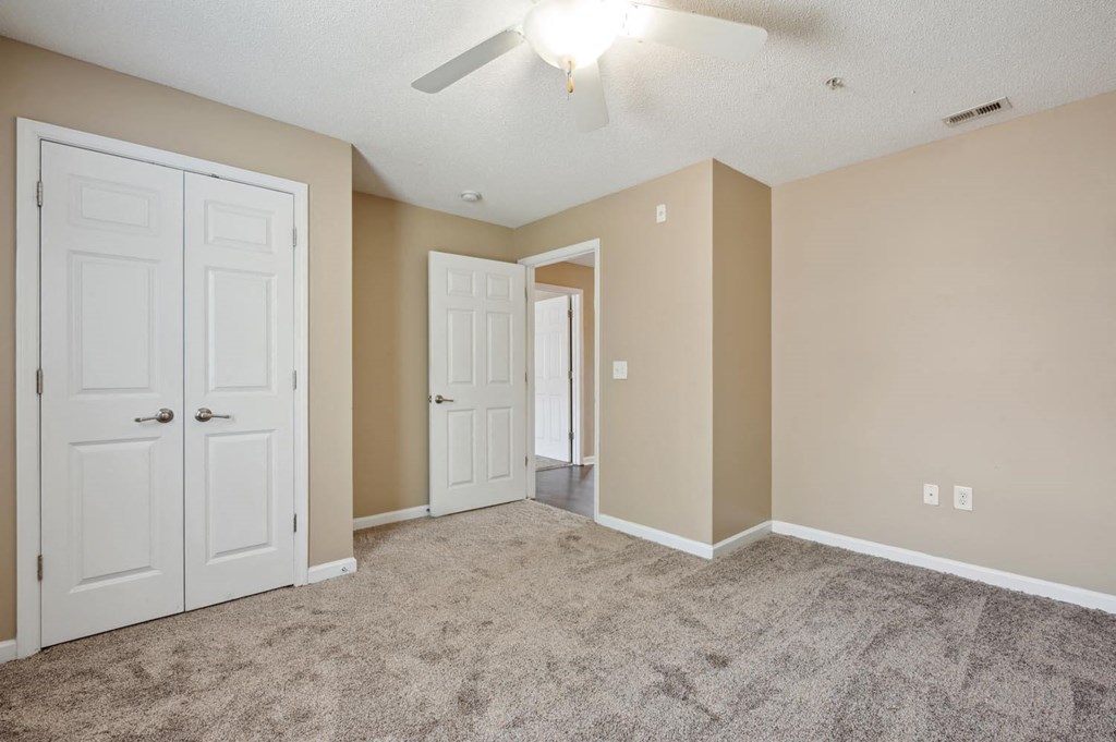 an empty living room with two doors and a ceiling fan