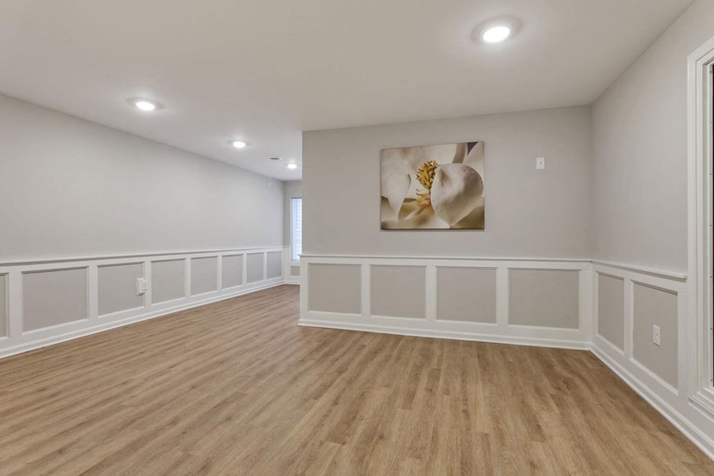 a living room with white walls and a painting on the wall