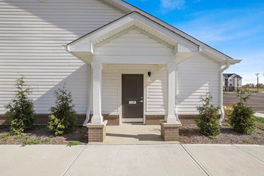 the front of a white house with a black door
