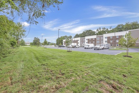 A grassy area with a road and buildings in the background.