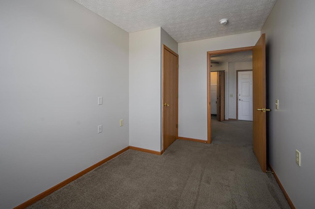 A hallway with carpeted flooring and white walls.