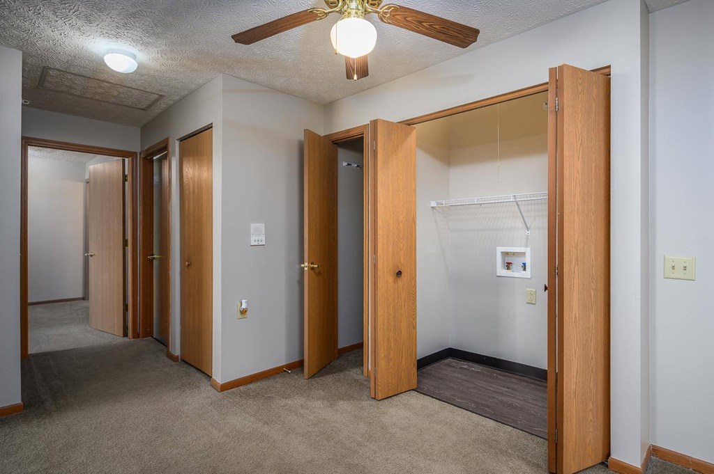 A room with a ceiling fan and a doorway leading to another room.