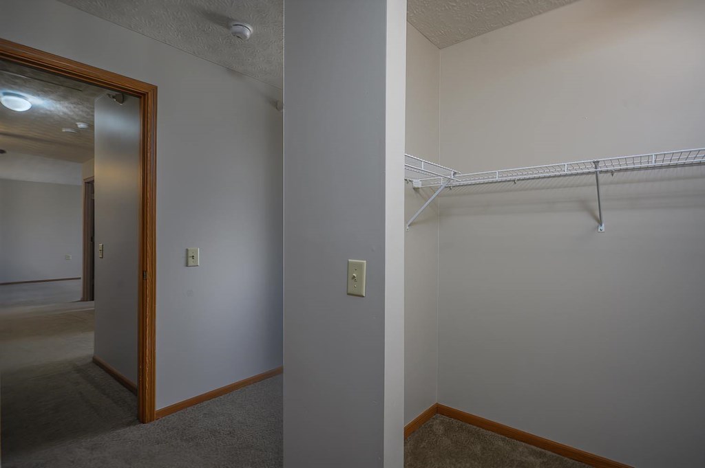 A white wall with a light switch and a white shelf.