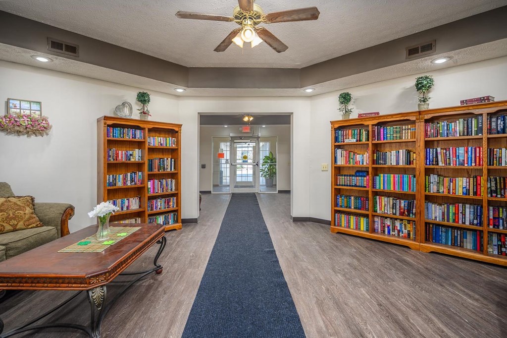 A room with a ceiling fan and bookshelves filled with books.
