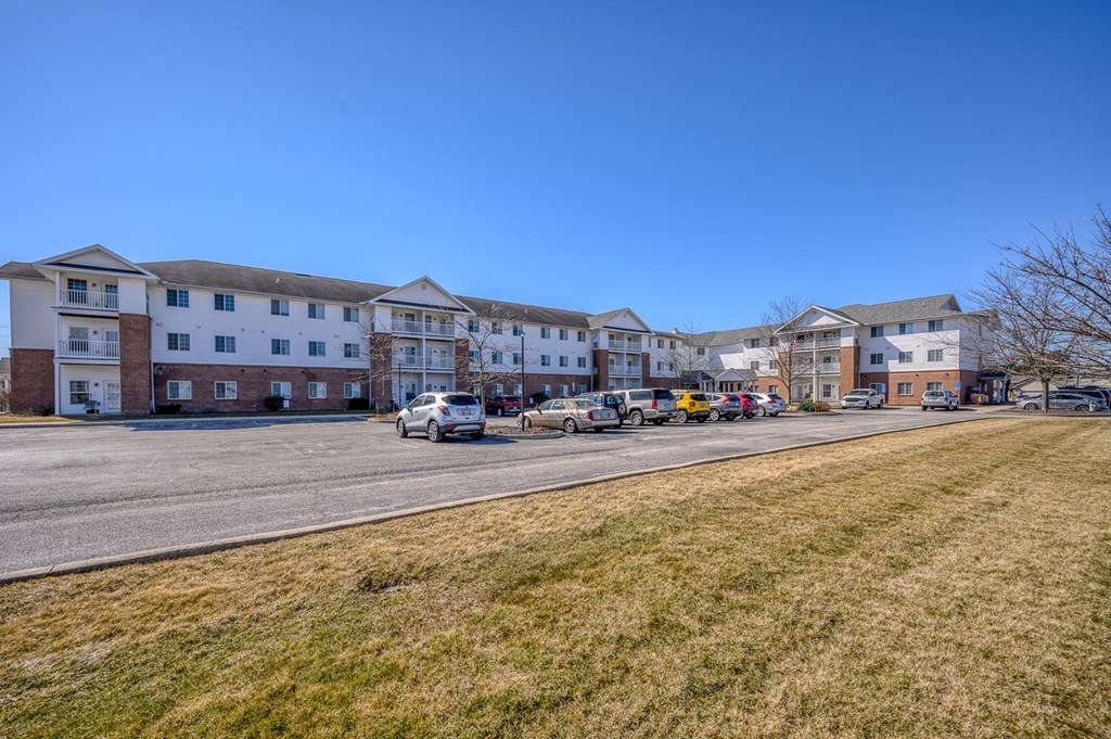 A row of apartment buildings with cars parked in front.