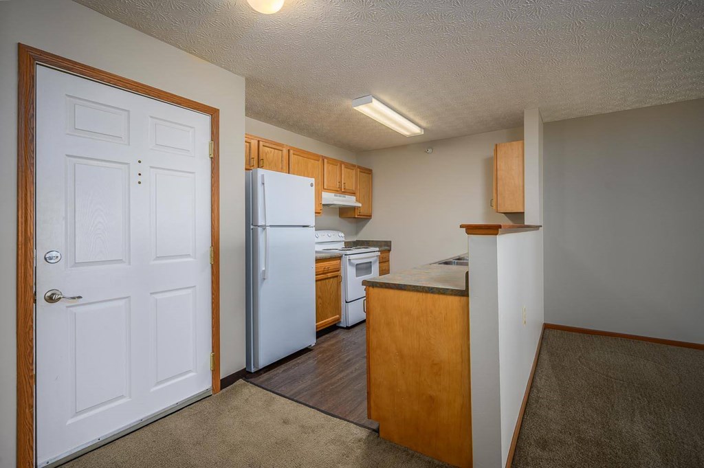 A kitchen with a white refrigerator and wooden cabinets.