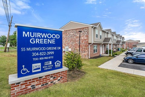 a sign in front of a building with apartments in the background