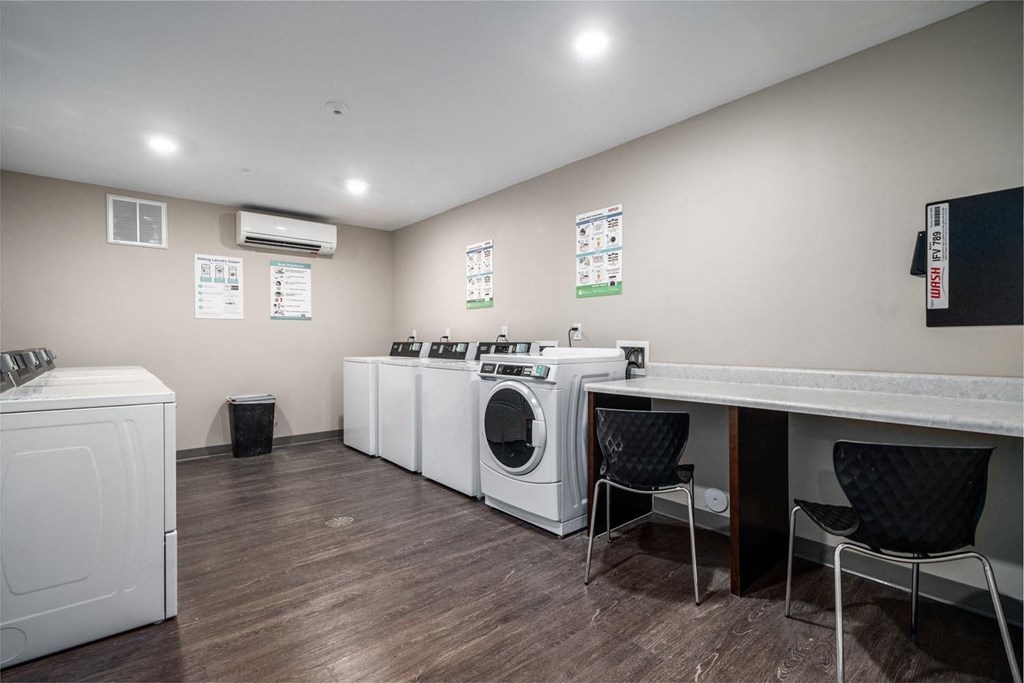 a laundry room with four washing machines and a counter with chairs
