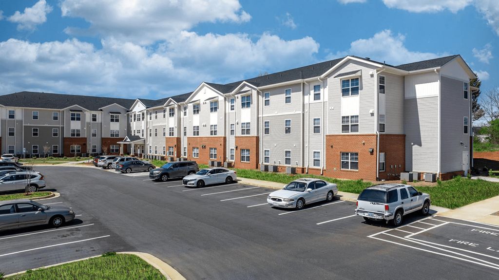 a parking lot with cars in front of an apartment building