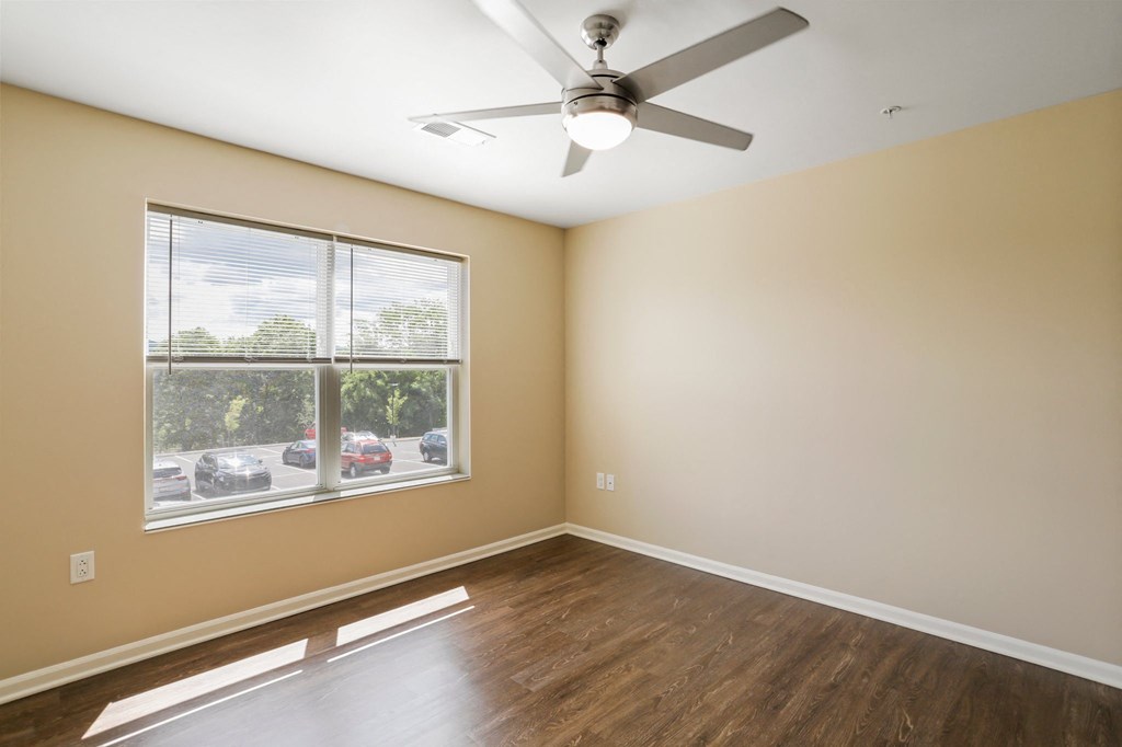 an empty bedroom with a ceiling fan and a large window
