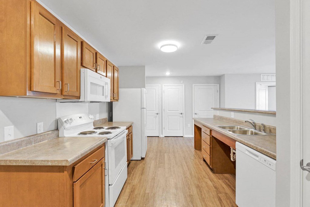 an empty kitchen with wooden cabinets and white appliances