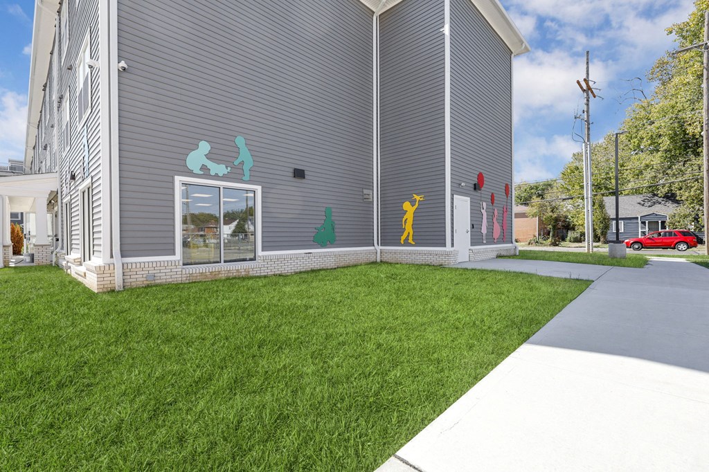 the front of a building with green grass and a sidewalk